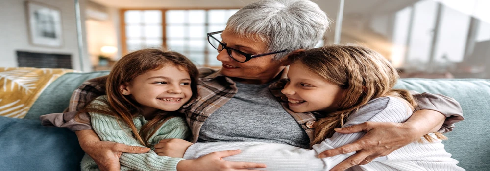 Oma umarmt ihre zwei Enkelinnen auf dem Sofa