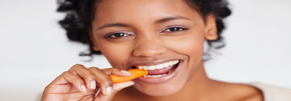Junge Frau beißt in eine Möhre