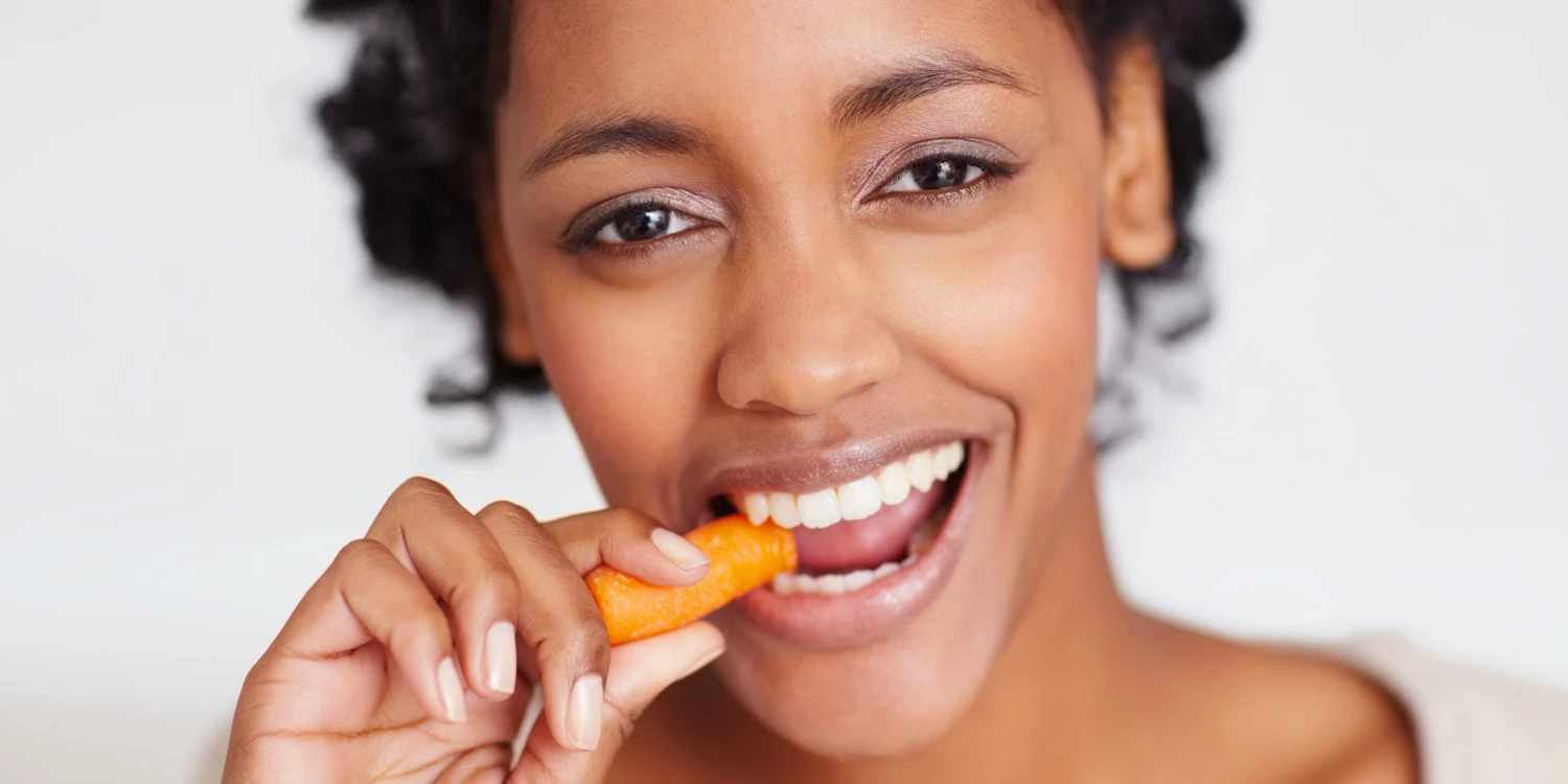 Junge Frau beißt in eine Möhre