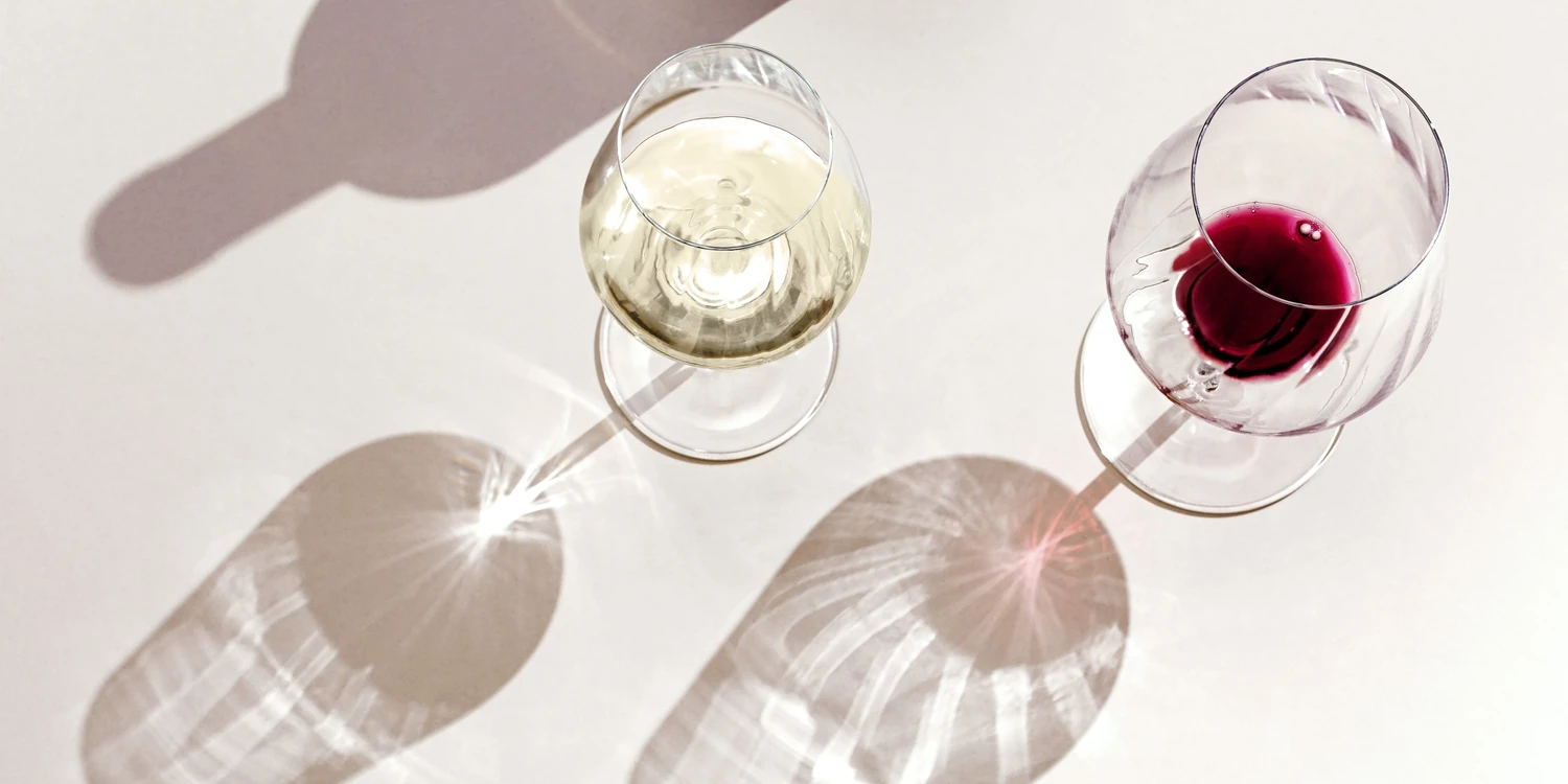 Zwei Weingläser werfen Schatten auf einen Tisch