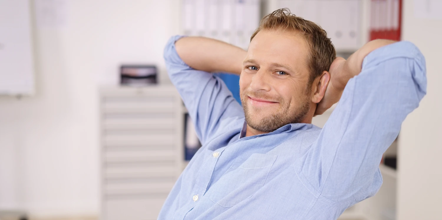 Mann sitzt am Schreibtisch und lehnt sich zurück