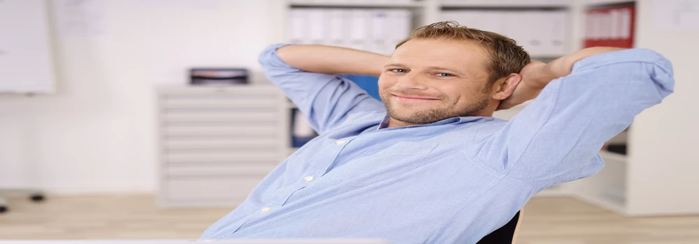 Mann sitzt am Schreibtisch und lehnt sich zurück