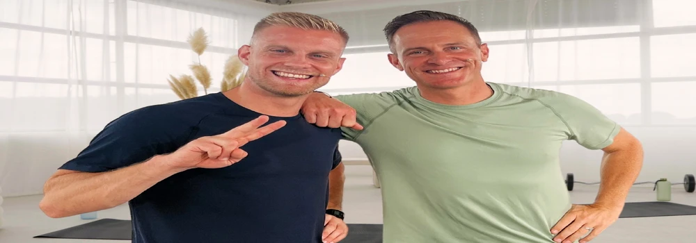 Zwei Fitnesstrainer grüßen, im Hintergrund liegen Yogamatten