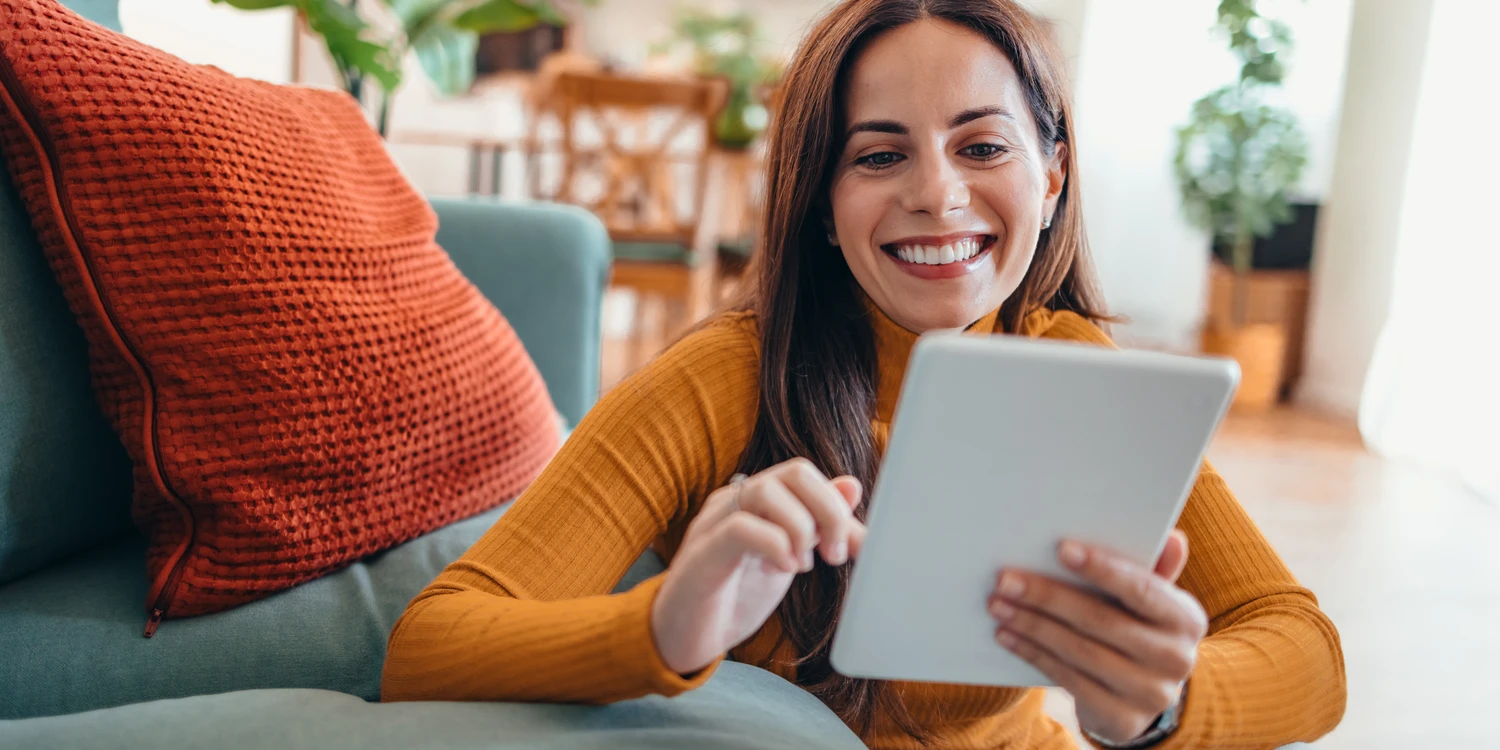 Frau mit Notepad Lächelnde Frau mit Notepad lehnt an einem Sofa