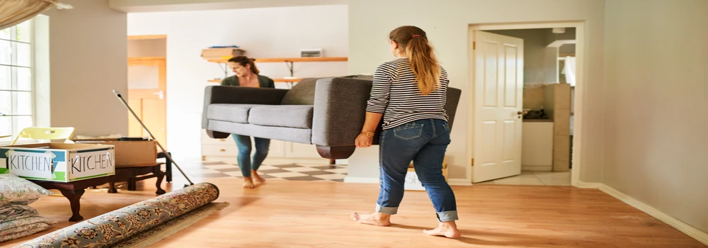 Freundinnen, die ein Sofa tragen