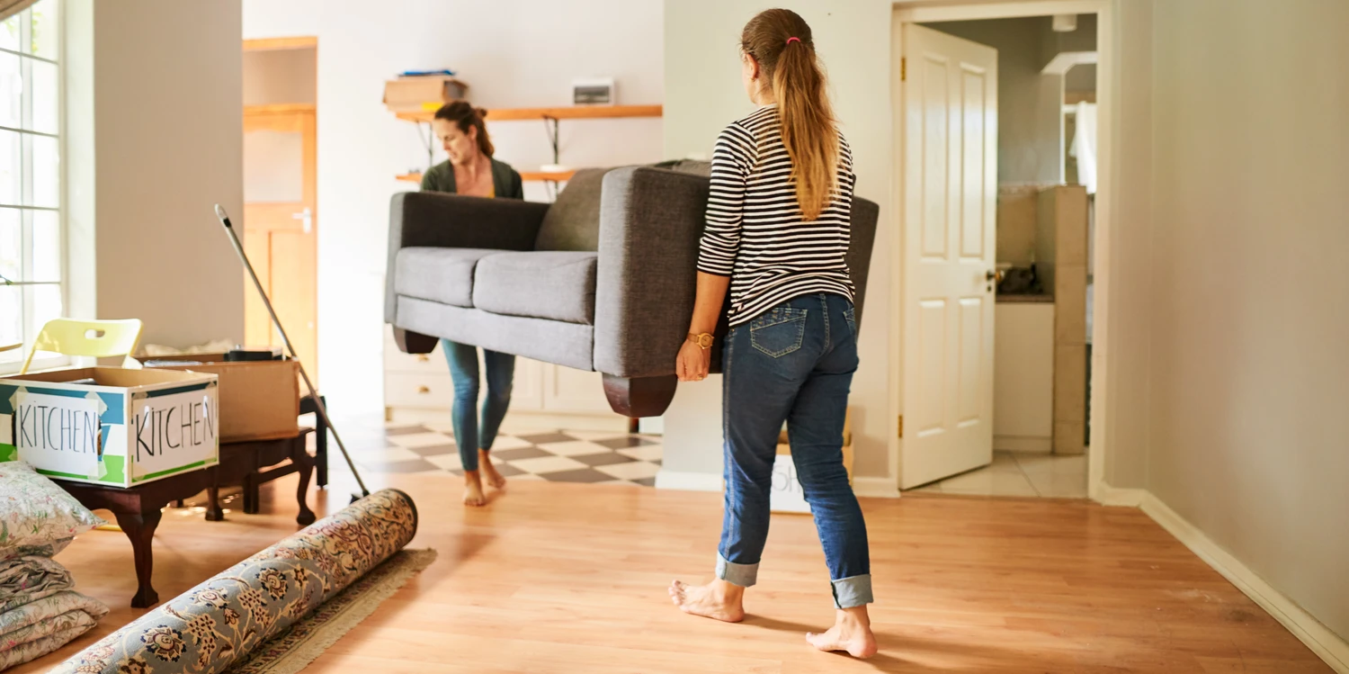 Freundinnen, die ein Sofa tragen