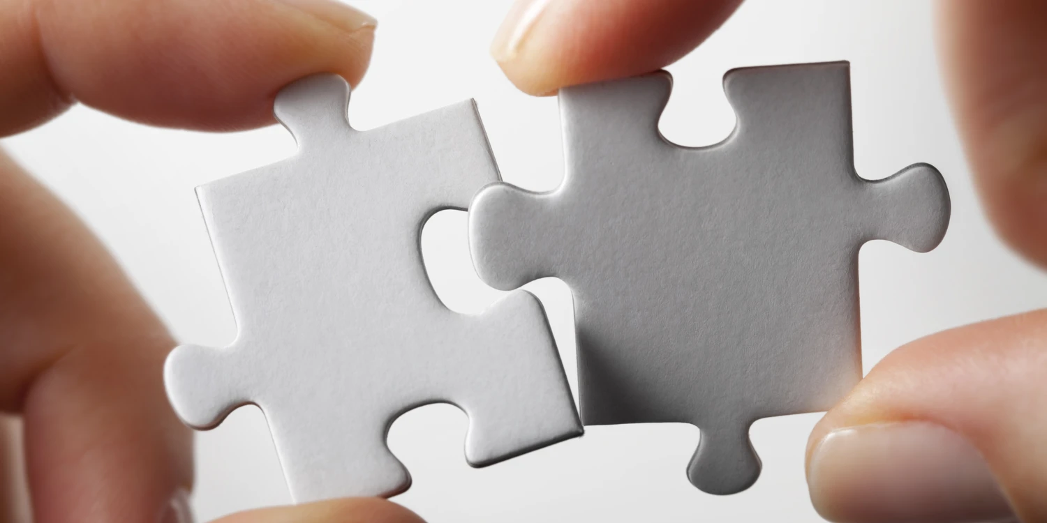 Zwei weiße Puzzleteile werden zusammengefügt