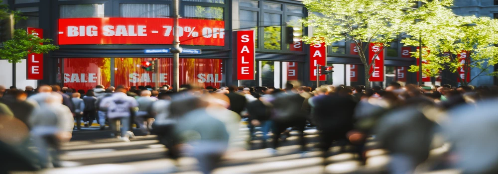 Menschen in einer Einkaufsmeile mit Sonderangebotshinweisen Sale