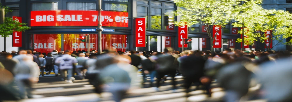 Menschen in einer Einkaufsmeile mit Sonderangebotshinweisen Sale