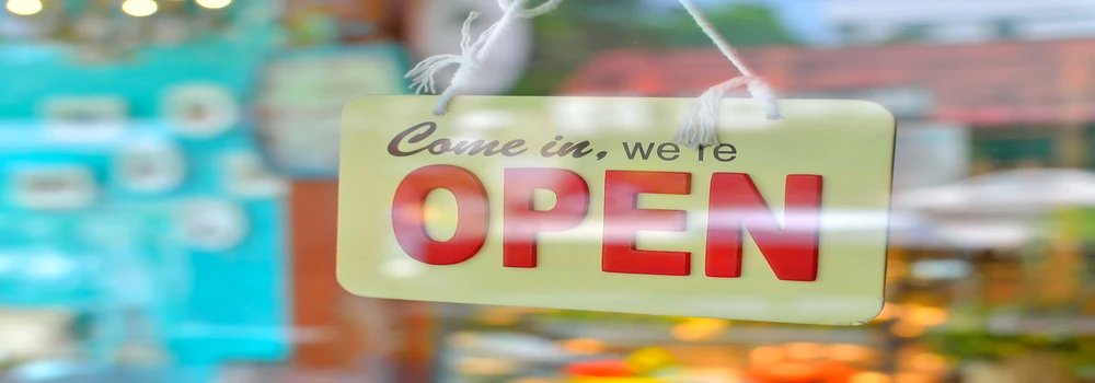 "We are open", Schild hinter einer Glastür