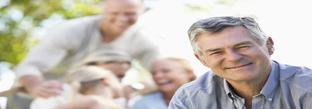 Erwachsener Mann schaut in die Kamera. Im Hintergrund sind weitere Personen.