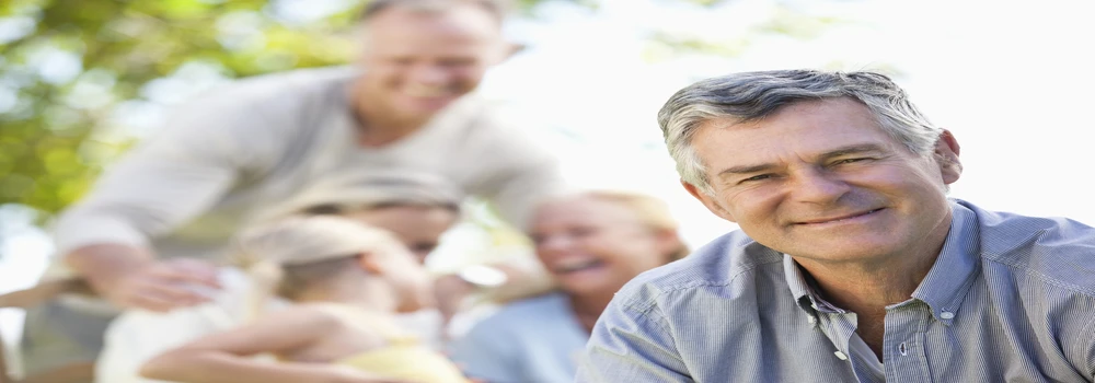 Erwachsener Mann schaut in die Kamera. Im Hintergrund sind weitere Personen.