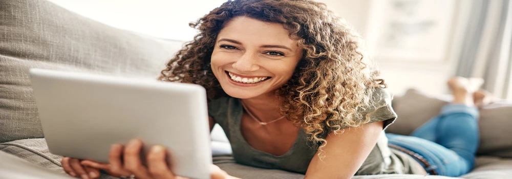 Frau liegt mit einem Notepad auf dem Sofa